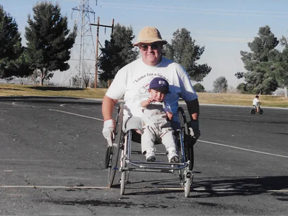 Founder of the University of Arizona's wheelchair basketball program, Rudy Gallego, and his son pose for a picture.