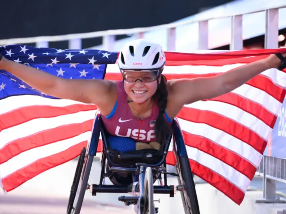 Photo of Paralympian Chelsea Stein racing and holding a US flag